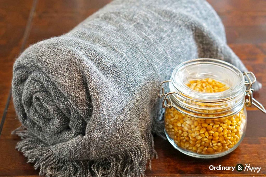 Popcorn kernels in a glass jar and a comfy blanket.