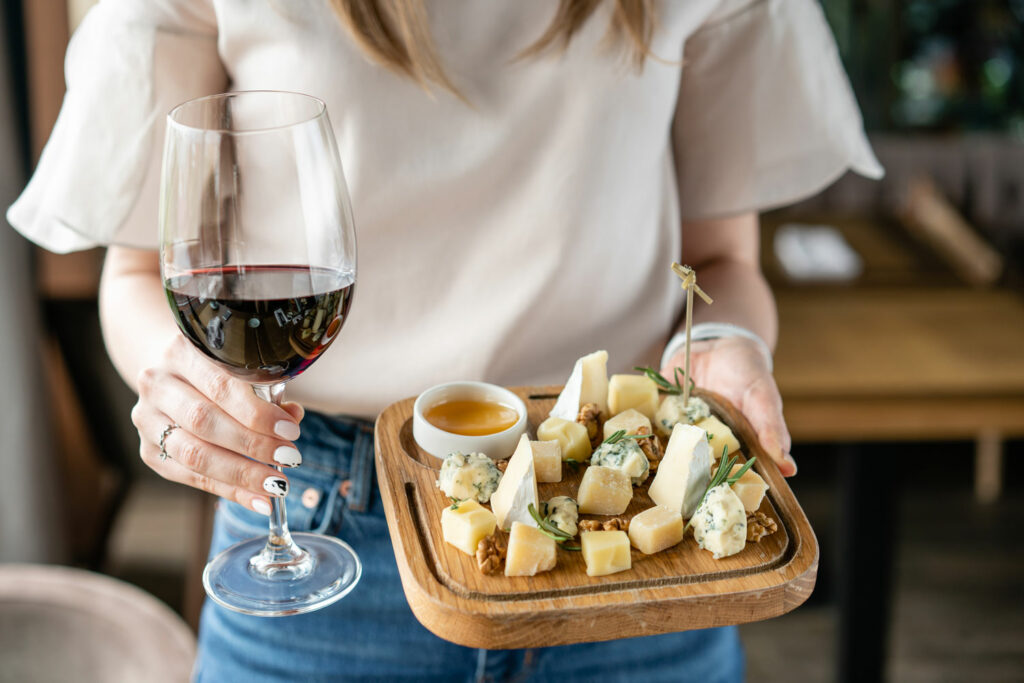 Woman holding a cheese board and a glass of wine